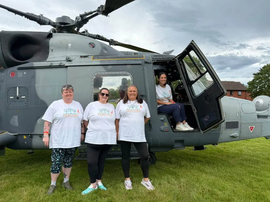 Peachy Striders posing with a helicopter